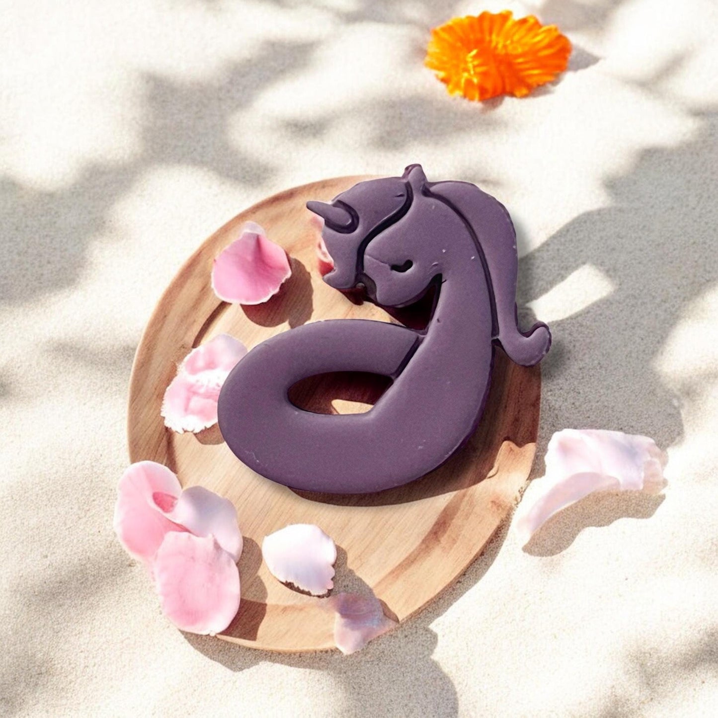 Flat lay of unicorn cutter with soft pink shells and beach shadows