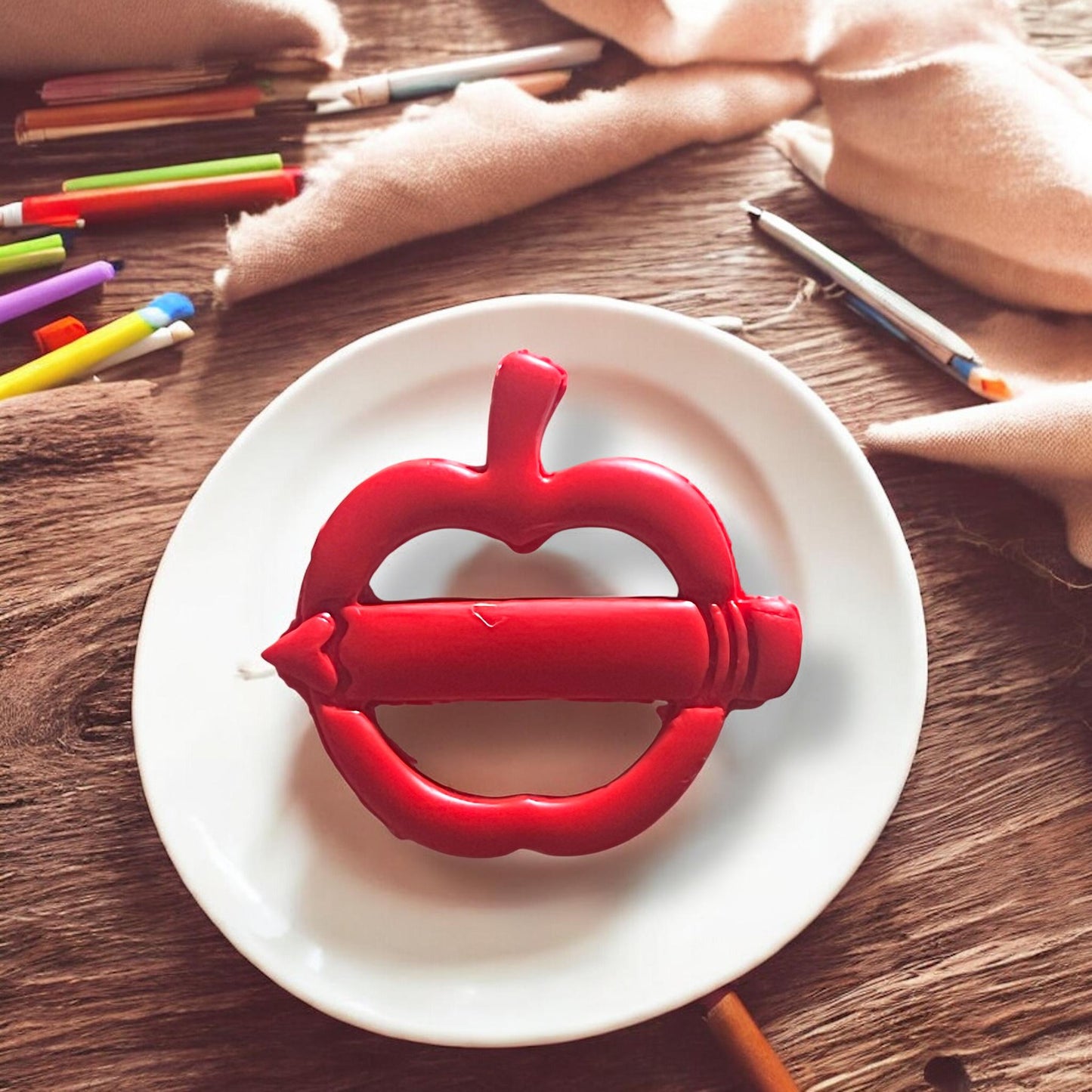 Finished apple pencil clay piece on a plate with colored pencils