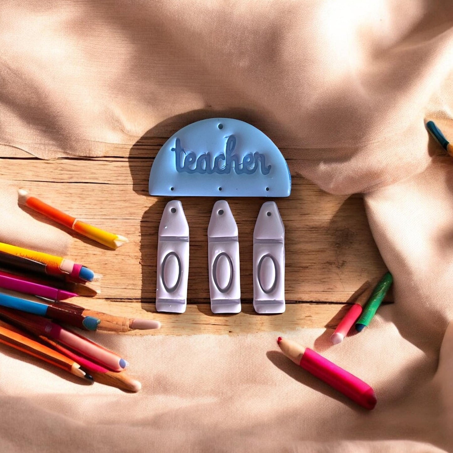 Fully assembled clay dangle layout on wood surface with colored pencils