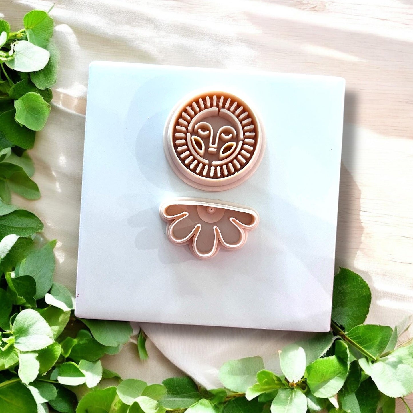 Set of two clay cutters — sun face and flower drop — displayed on tile