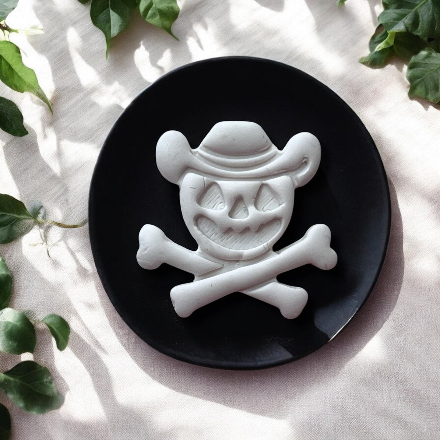 Halloween cowboy skull clay piece on black plate with greenery