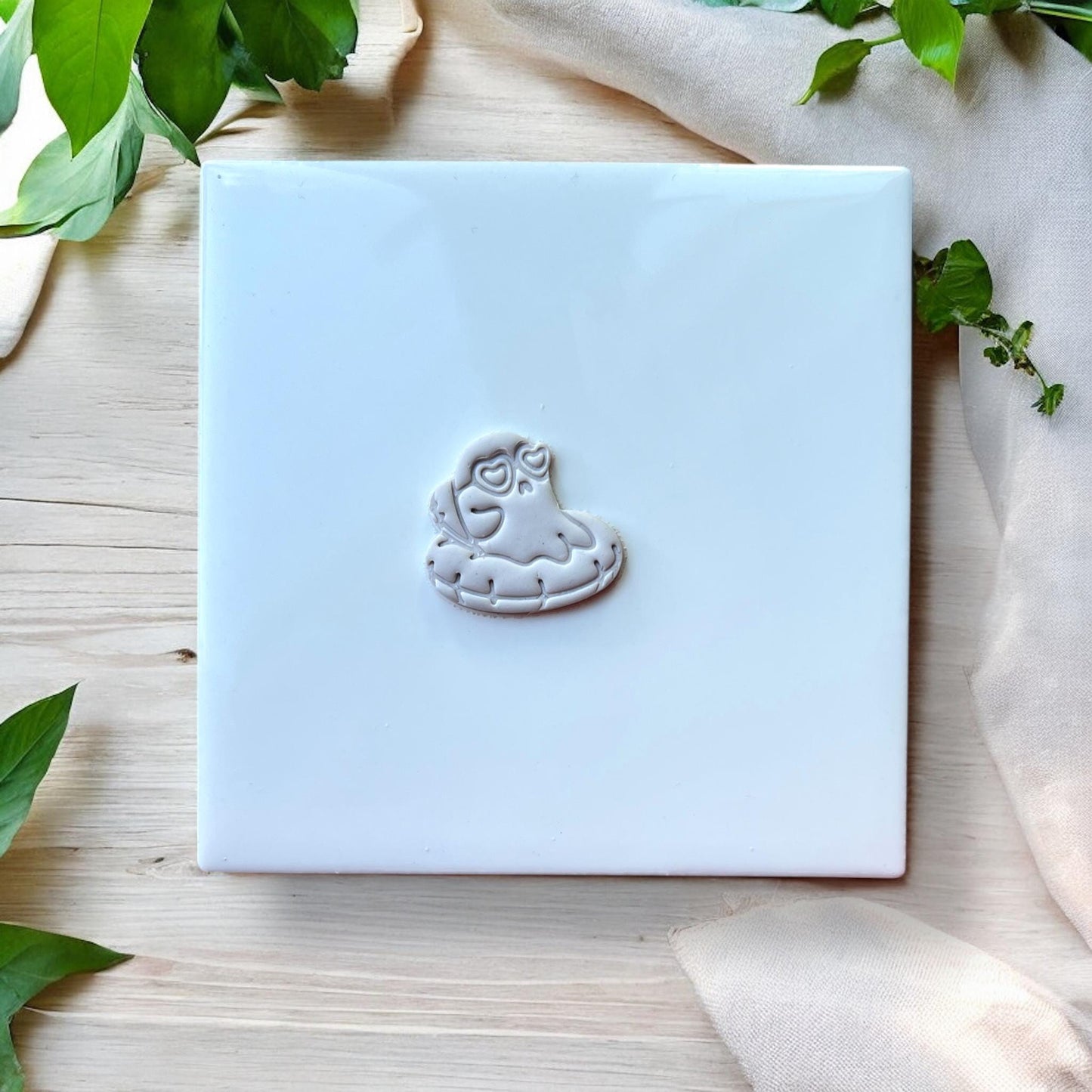 Close-up of grey clay ghost on floatie earring imprint