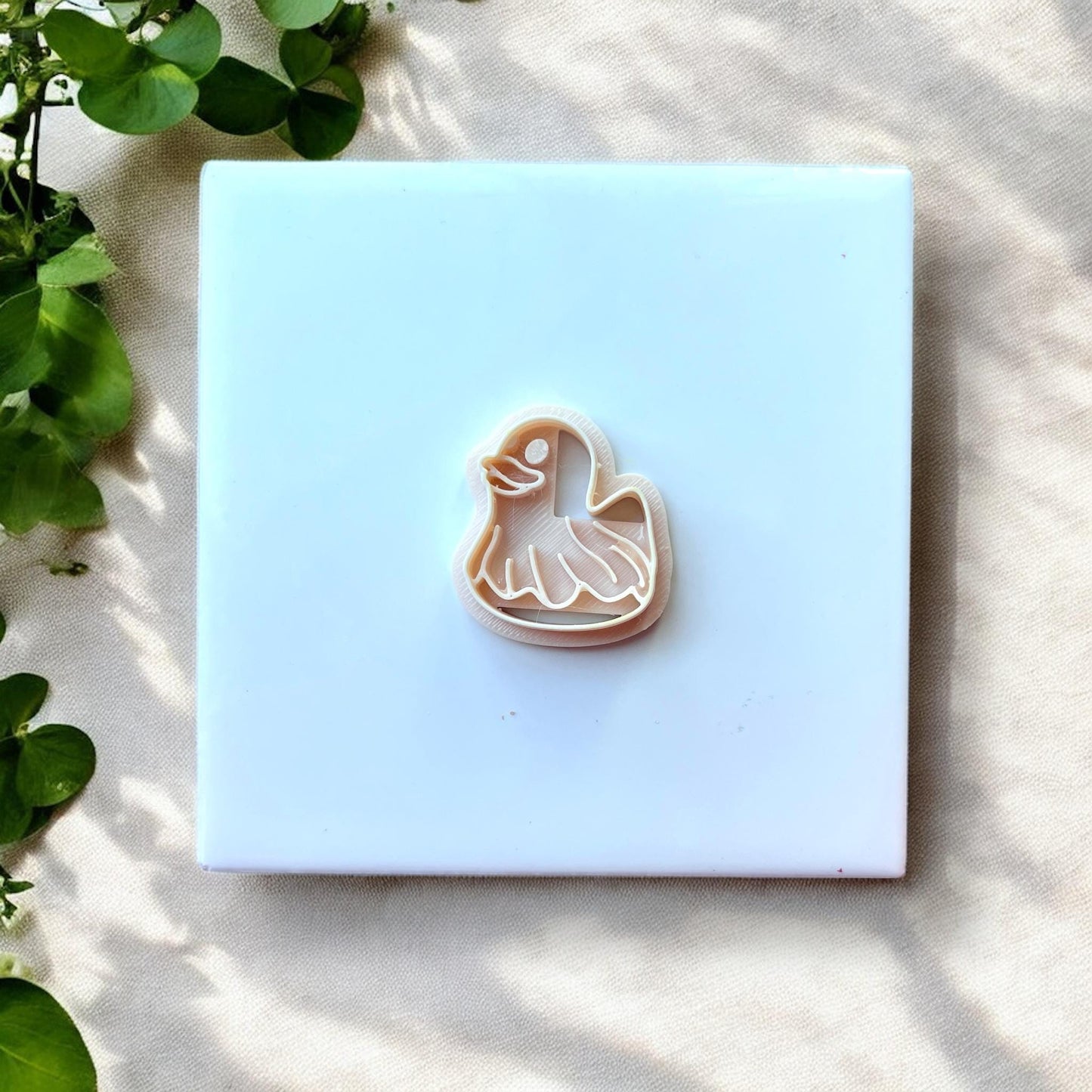 Duck floatie polymer clay cutter on white tile