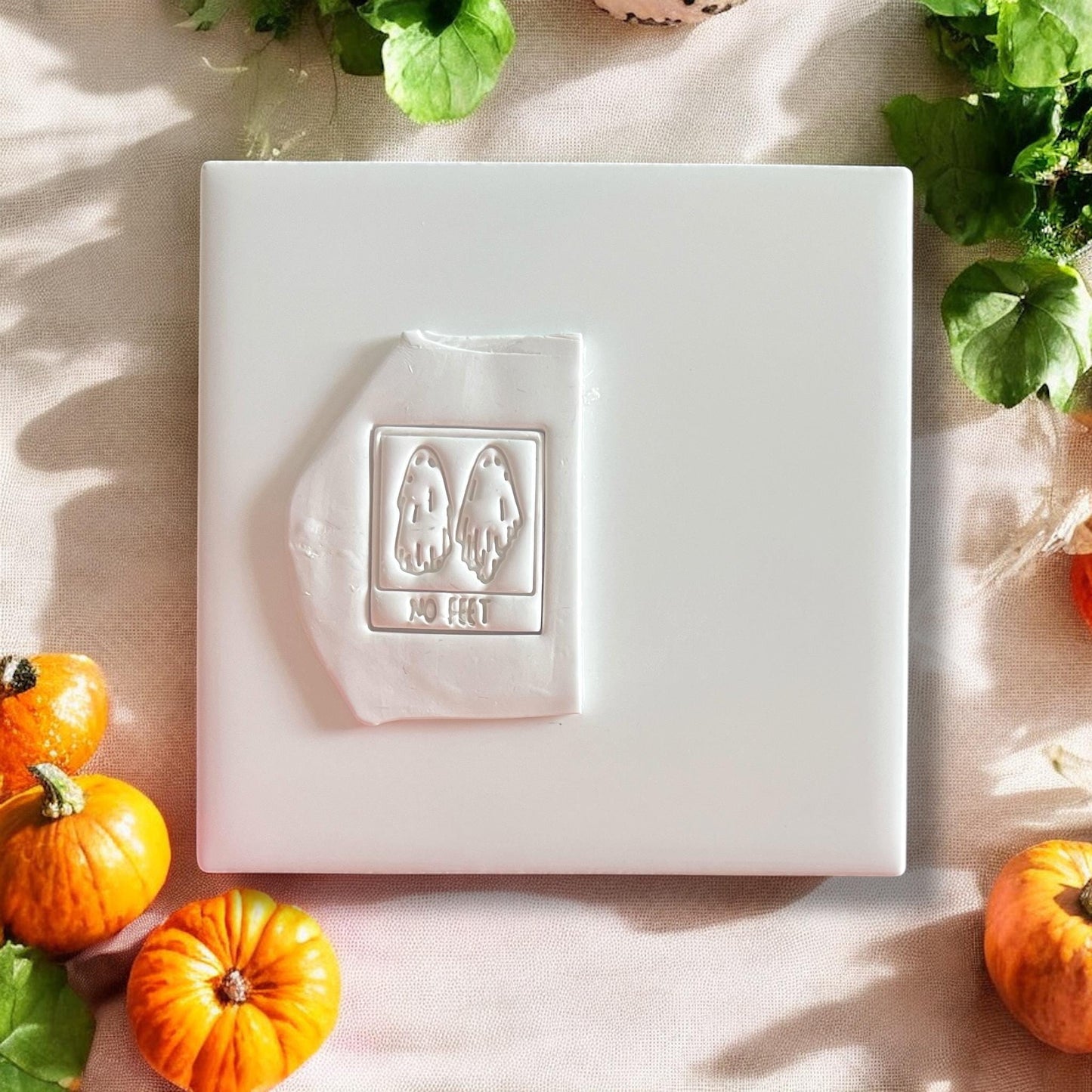 Ghost polymer clay cutter with “No Feet” text pressed into white clay