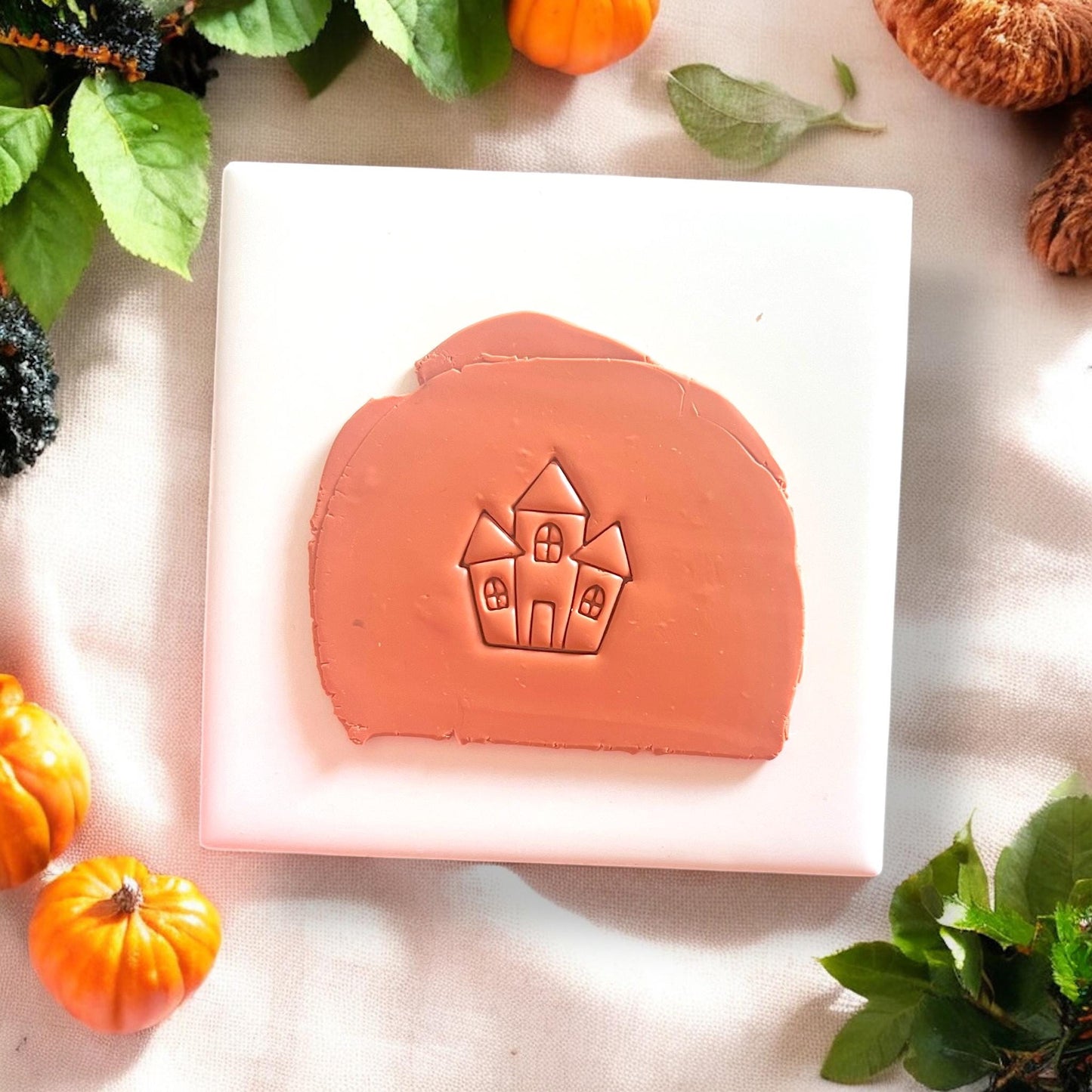 Orange clay slab with haunted house design impression
