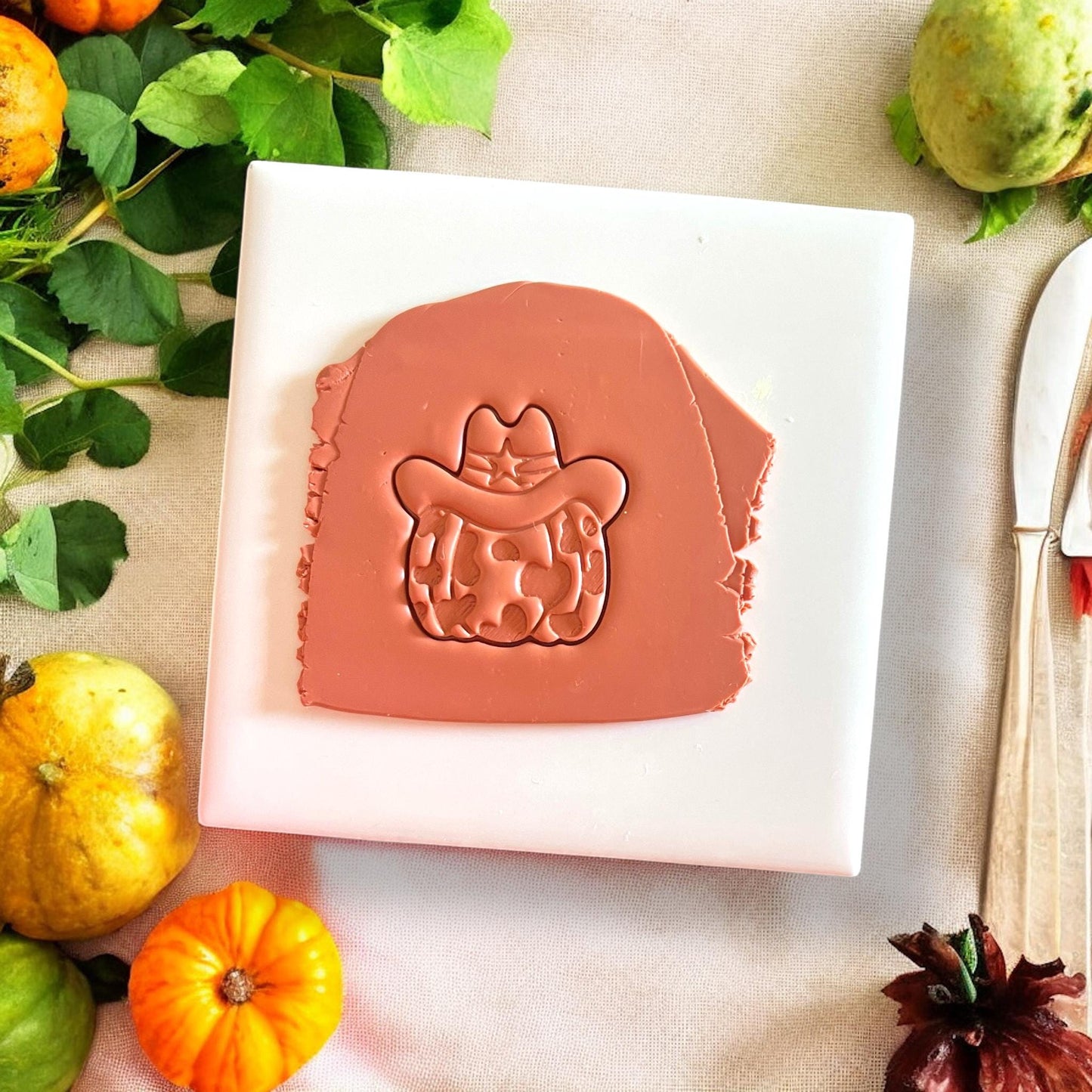 Cowprint pumpkin clay slab with sheriff hat imprint on wooden plate