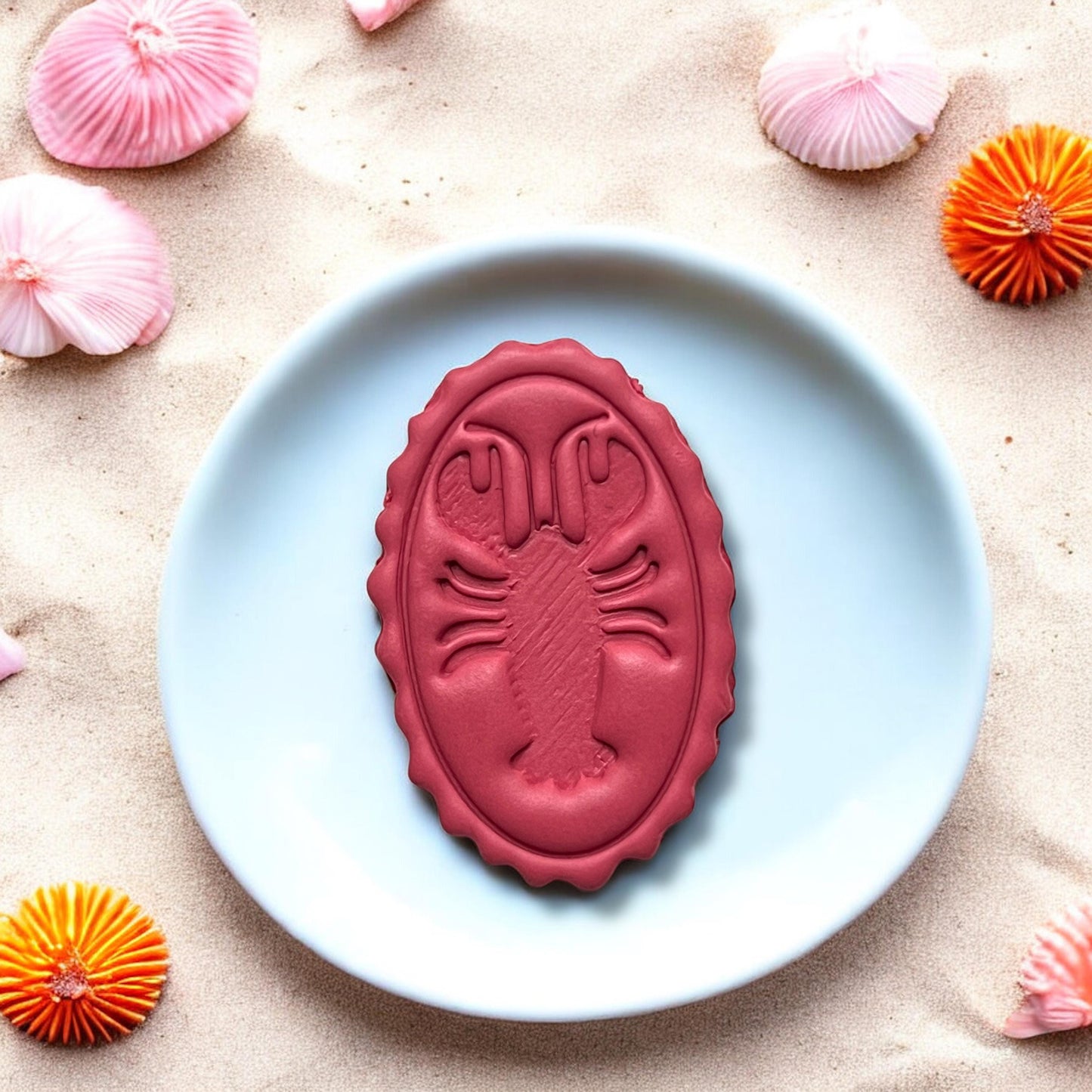 Large completed lobster oval charm displayed on plate with beach decor