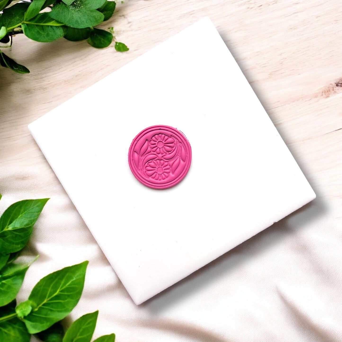 Floral round cutter impressed into pink clay slab