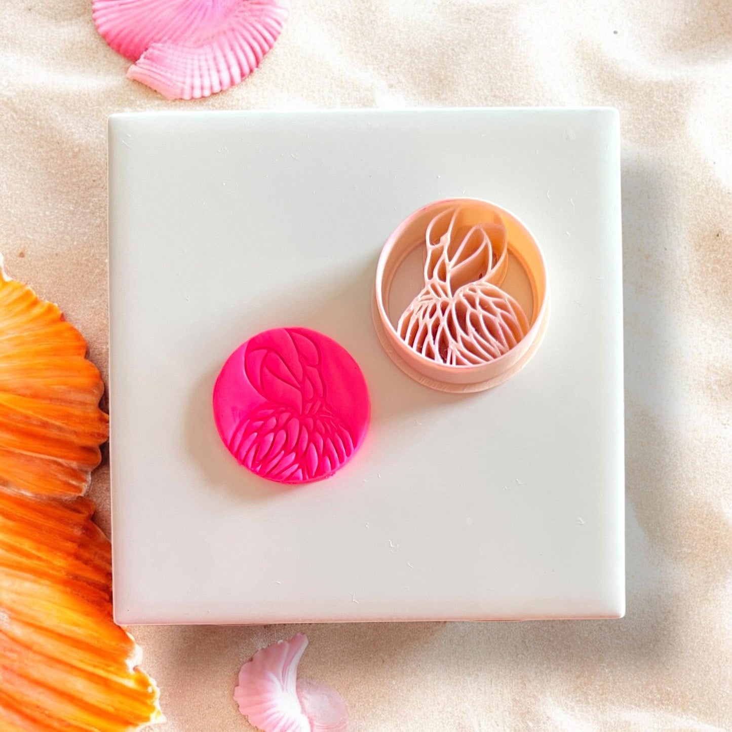 Cutter beside pink clay flamingo impression on white tile