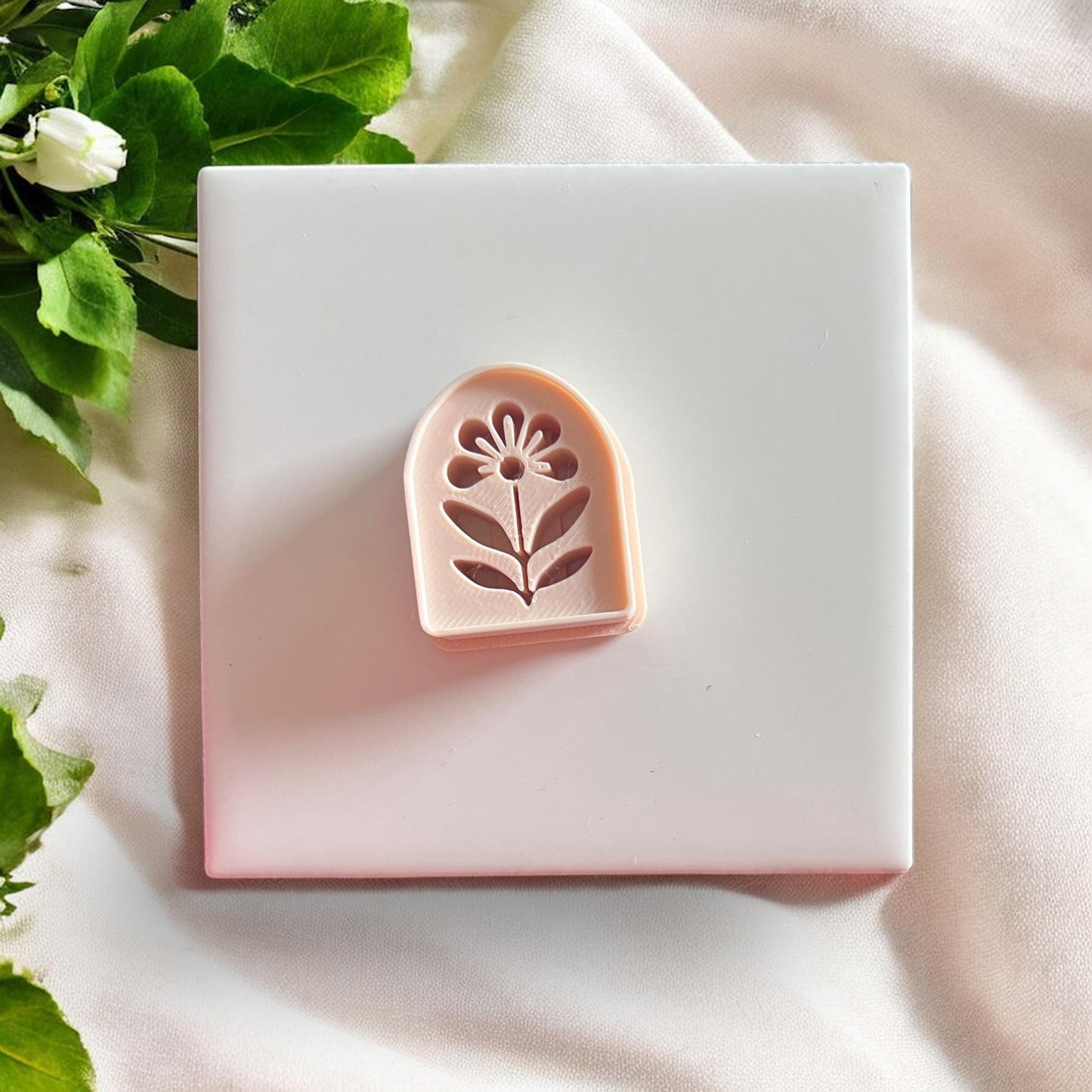 Peach-colored floral arch cutter on white tile