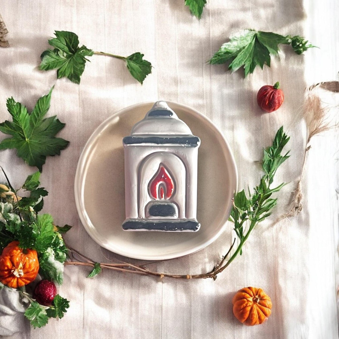 Large painted polymer clay lantern earring styled on ceramic dish with pumpkins and greenery