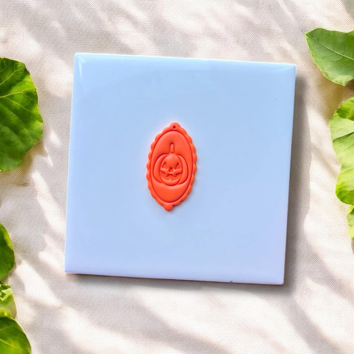 finished oval clay charm with jack-o'-lantern face