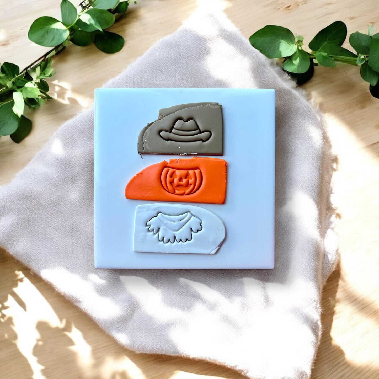 Three separate debossed clay impressions: cowboy hat, pumpkin face, and ghost collar