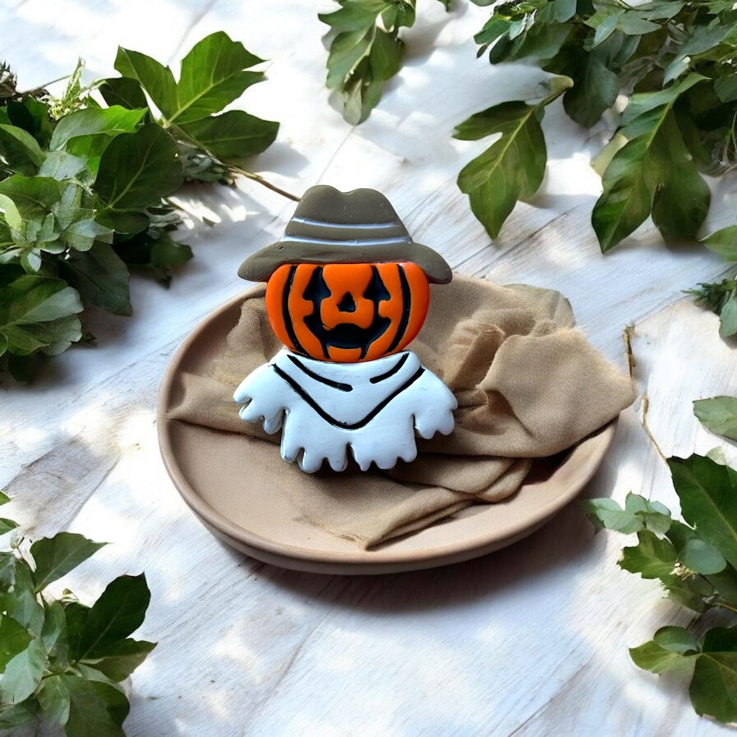 Finished multicolor pumpkin ghost cowboy earring displayed on a plate