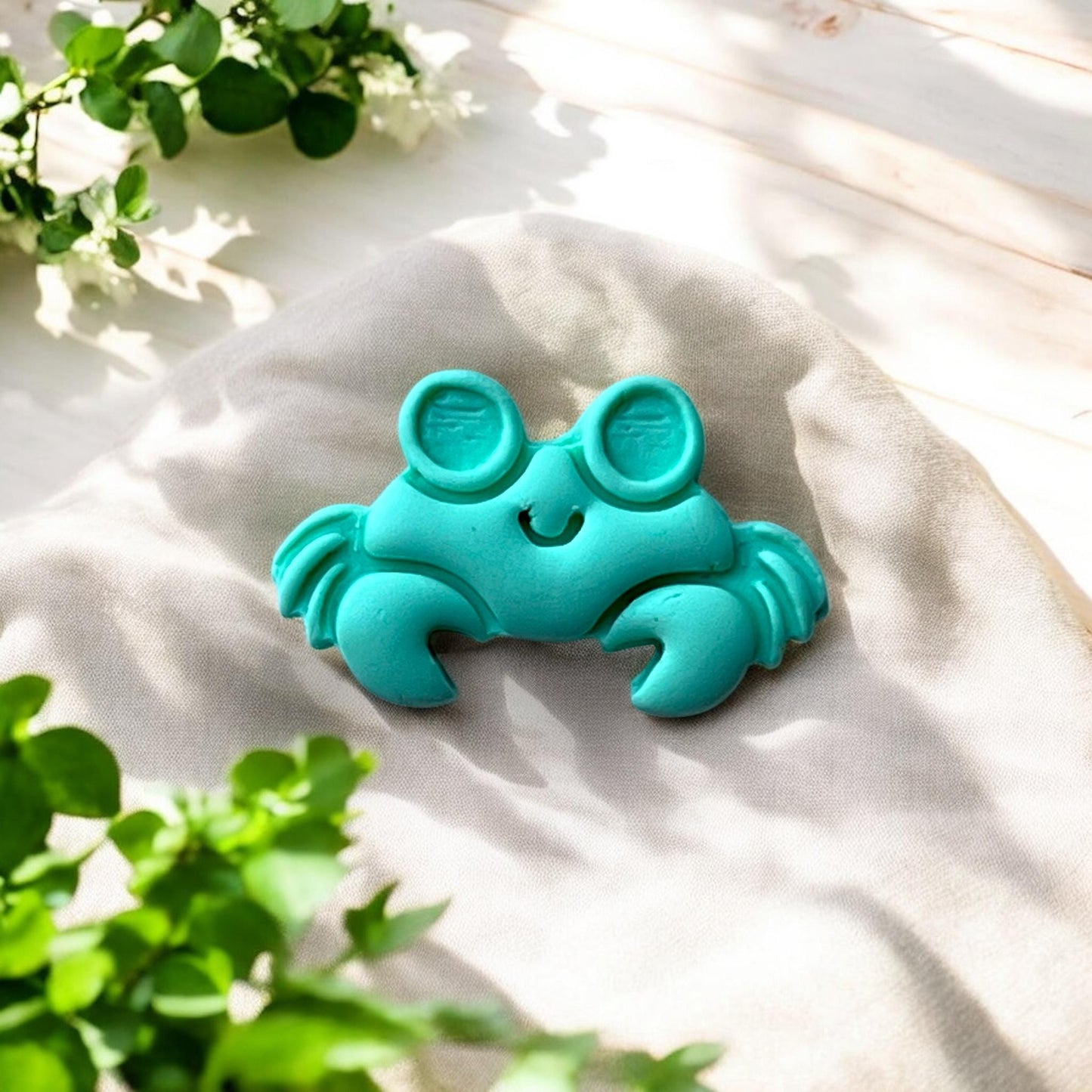 Close-up of smiling big-eye crab clay earring on fabric