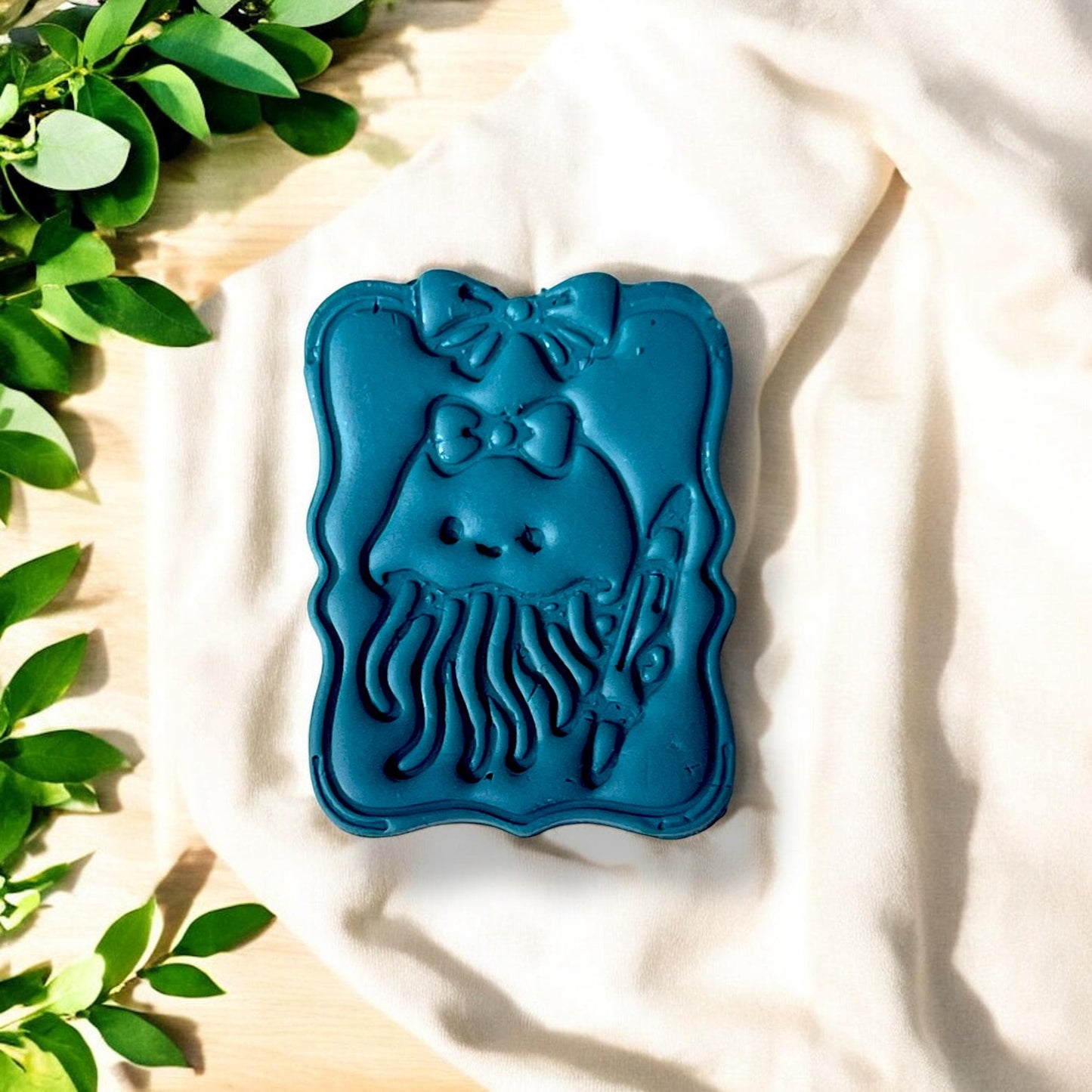 Finished jellyfish design on clay slab, surrounded by leaves