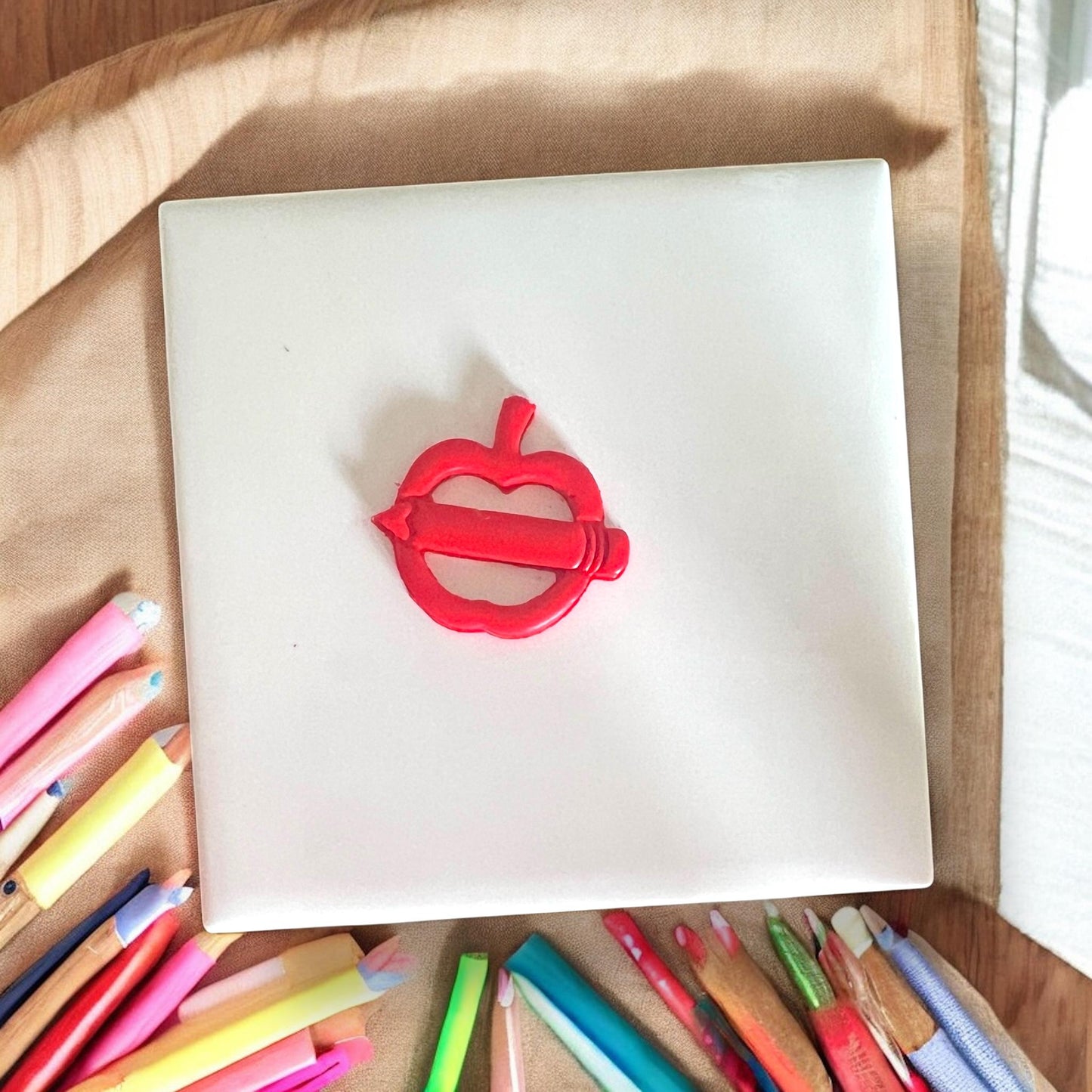 Finished clay cutout in apple and pencil shape on white background