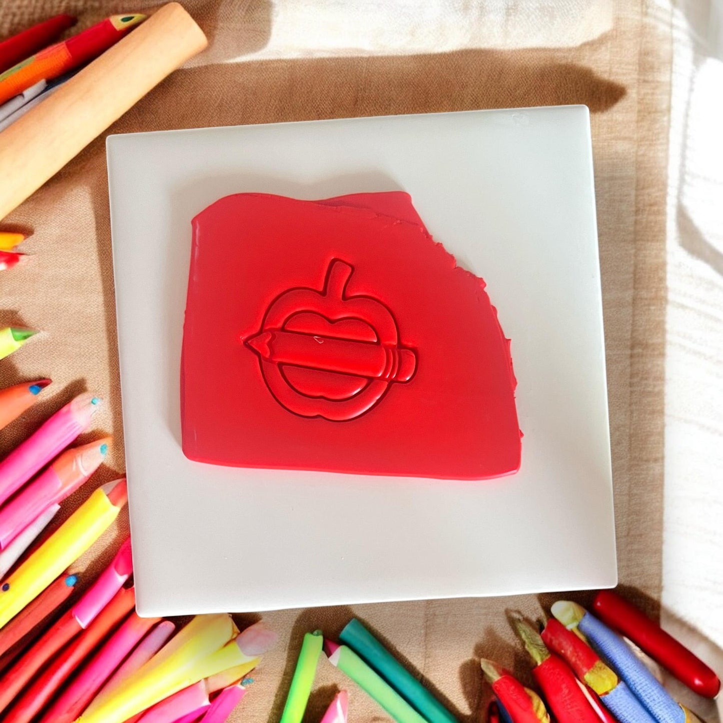 Red clay slab with apple and pencil silhouette impression