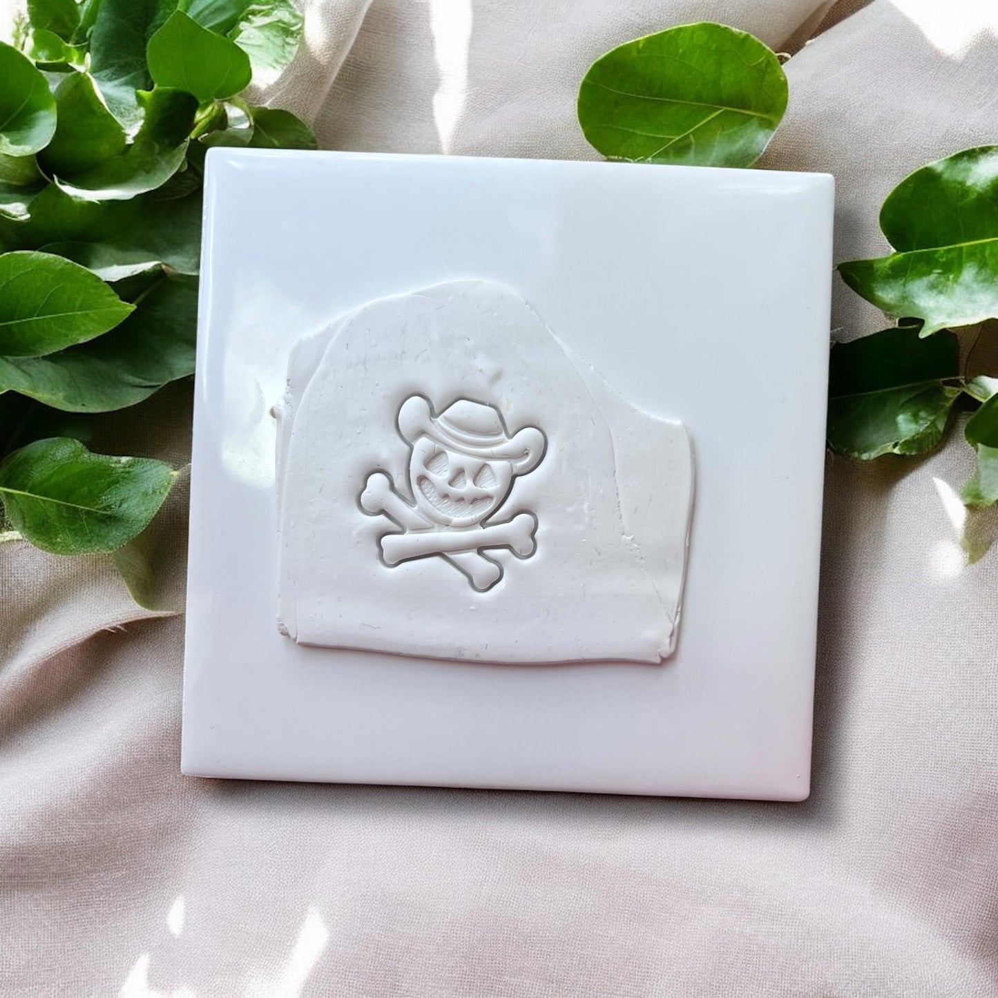 White clay slab with cowboy pumpkin skull and crossbones impression