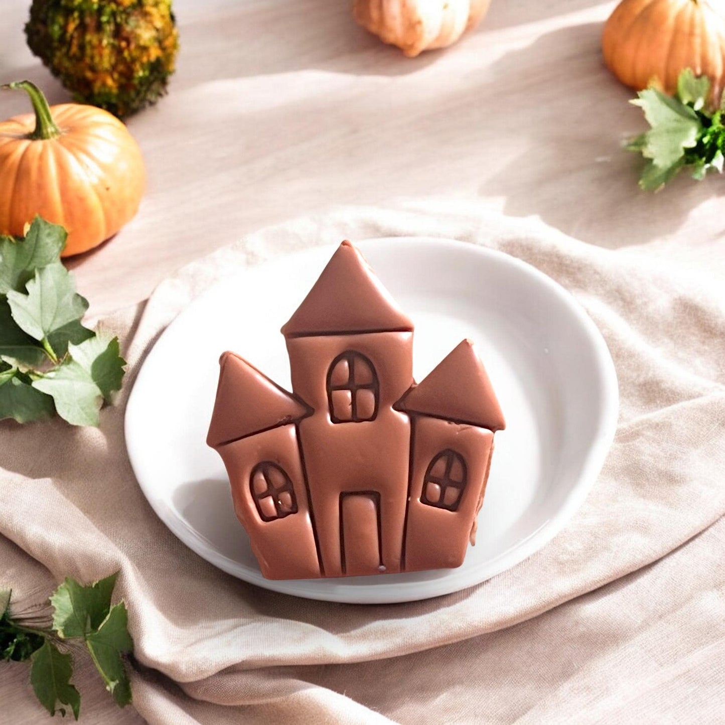 Finished haunted house clay piece on a white plate with pumpkins and leaves