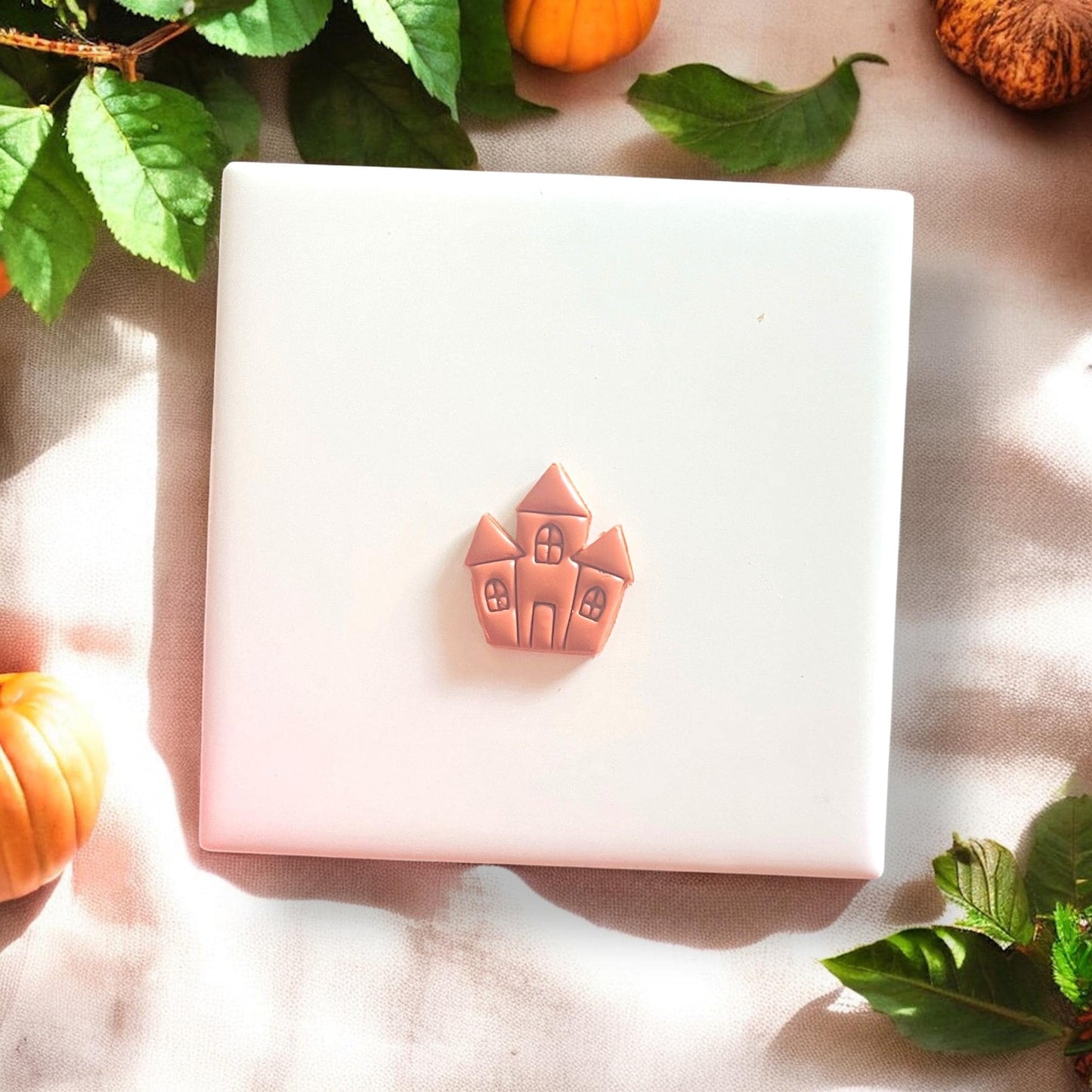 Finished haunted house clay piece centered on white tile