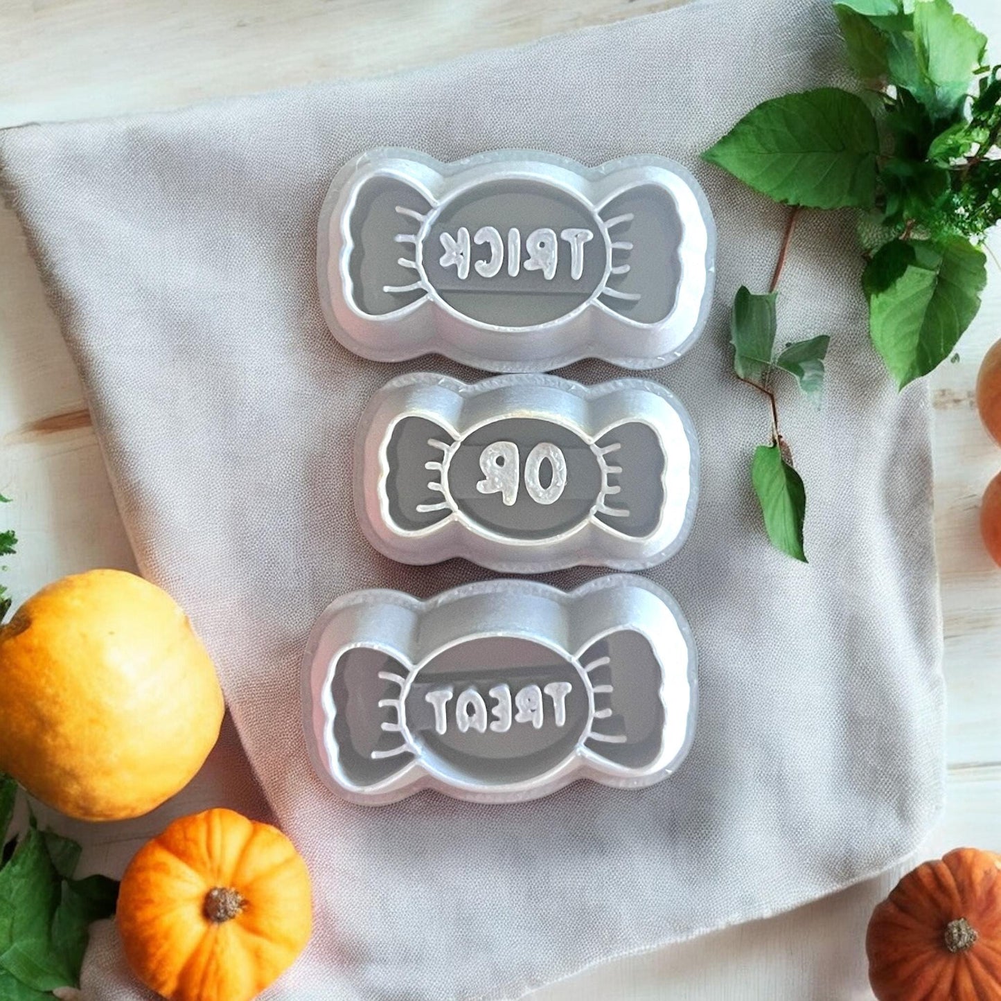 Gray Trick, Or, and Treat candy cutters displayed on fabric