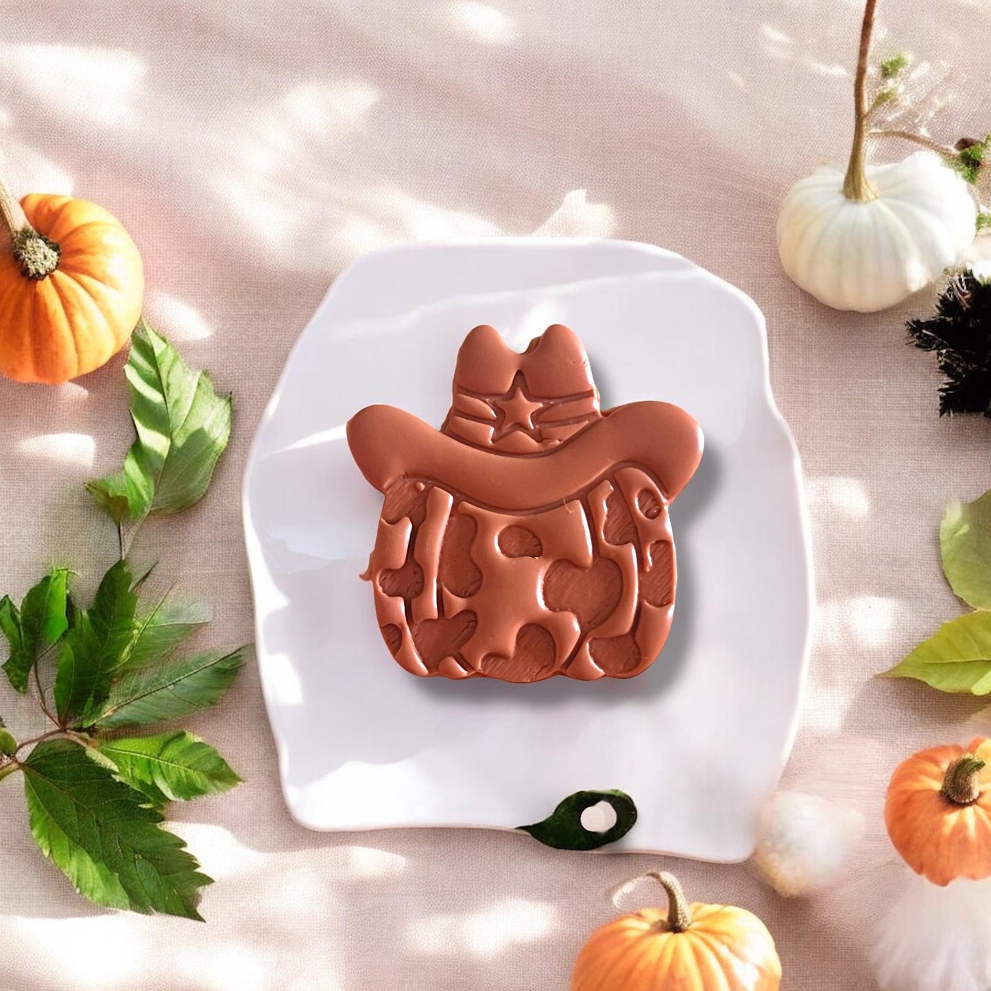 Finished clay earring piece in pumpkin sheriff shape displayed on white tile
