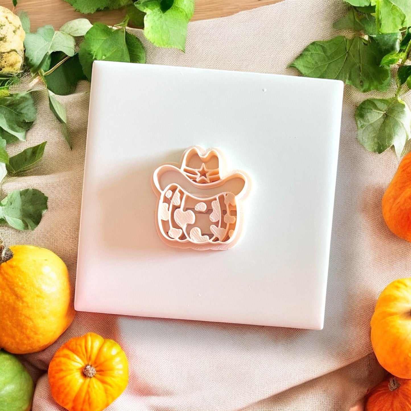 Clay impression and cutter of cowprint pumpkin sheriff on tile with fall props