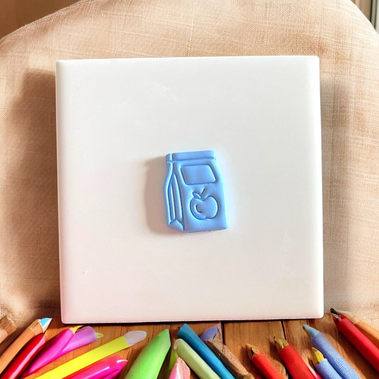 straight-on view of blue clay lunch bag impression with colored pencils