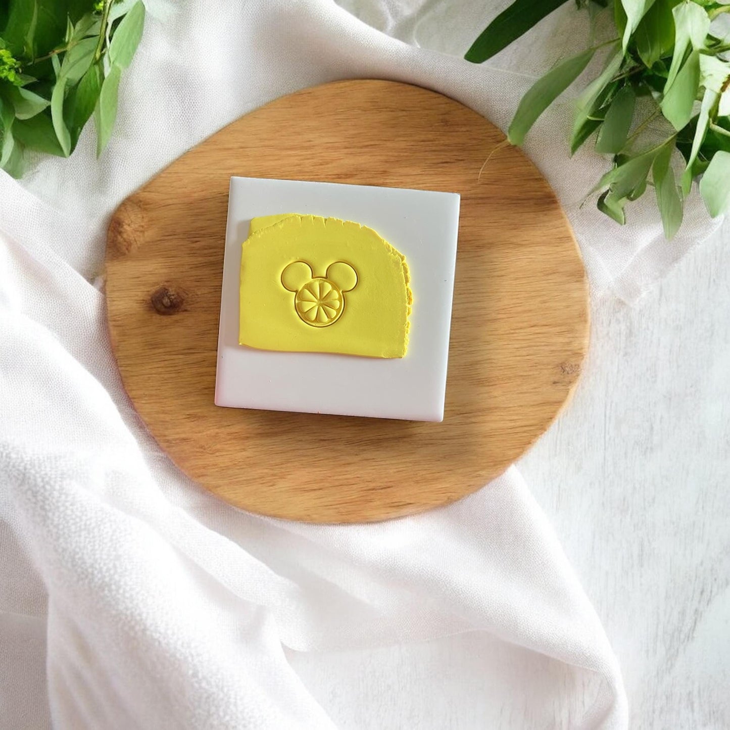 Clay cutter shaped like citrus mouse head on yellow clay