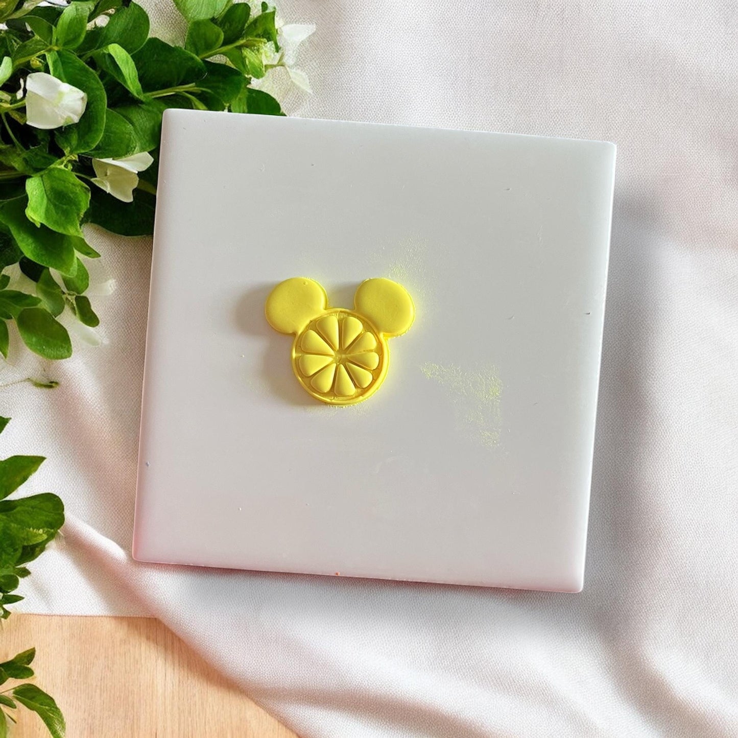 Orange slice mouse head cutter on white tile with greenery