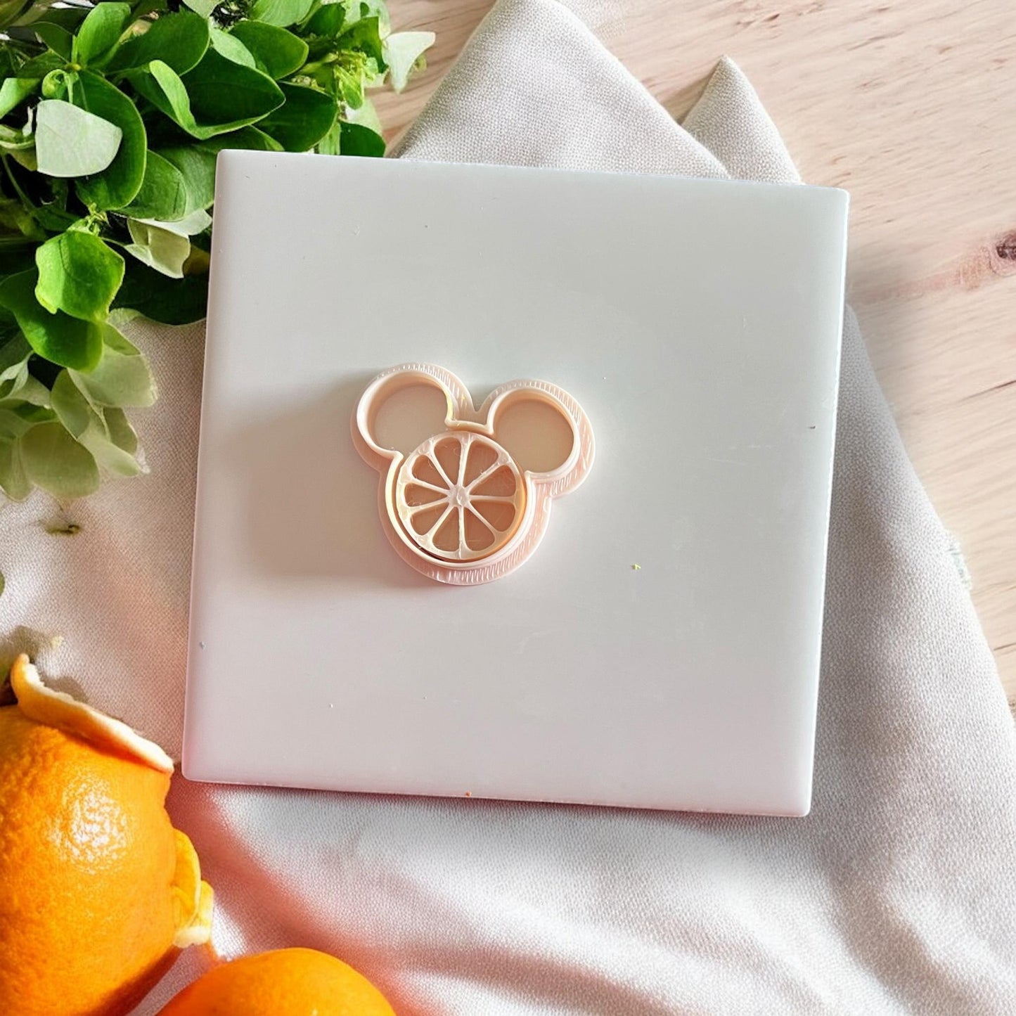 Yellow citrus mouse clay impression centered on white tile