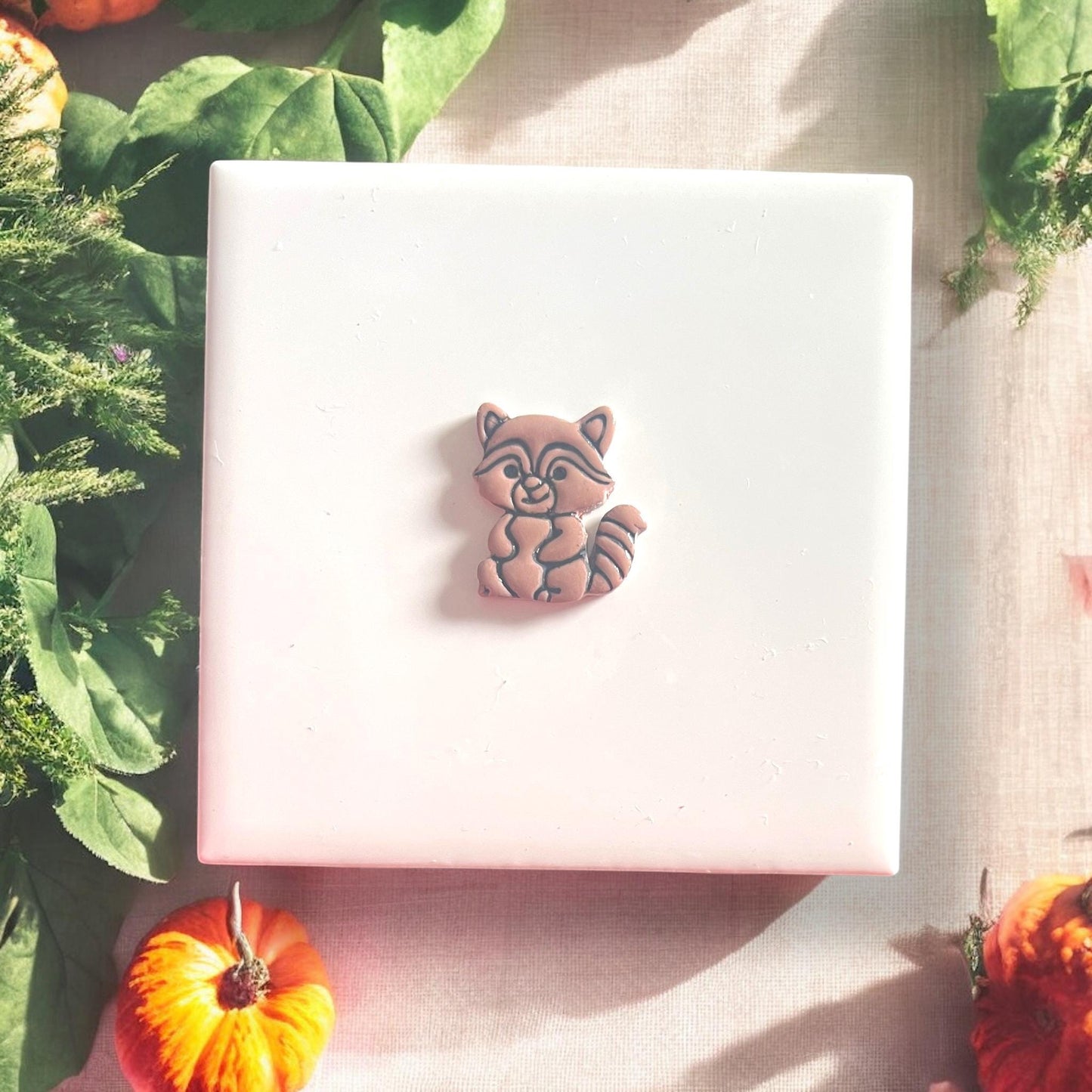 Finished raccoon clay earring with painted black outline for detailing