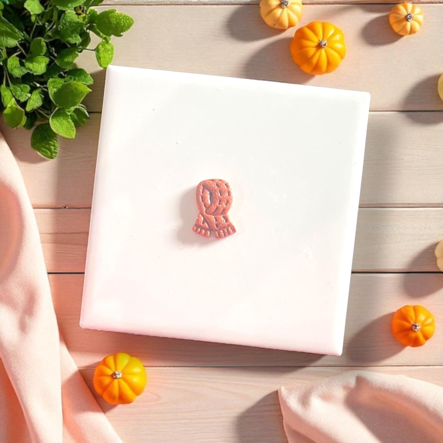 Finished clay earring cut from fall scarf mold surrounded by mini pumpkins