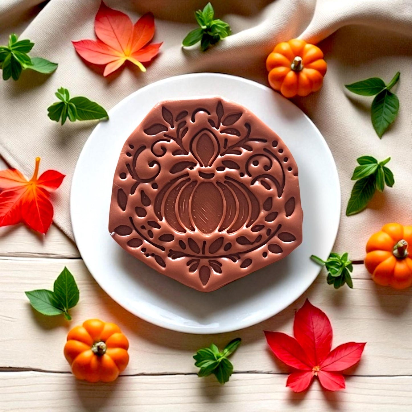 Ornate pumpkin earring design made from clay on a white plate with fall decor