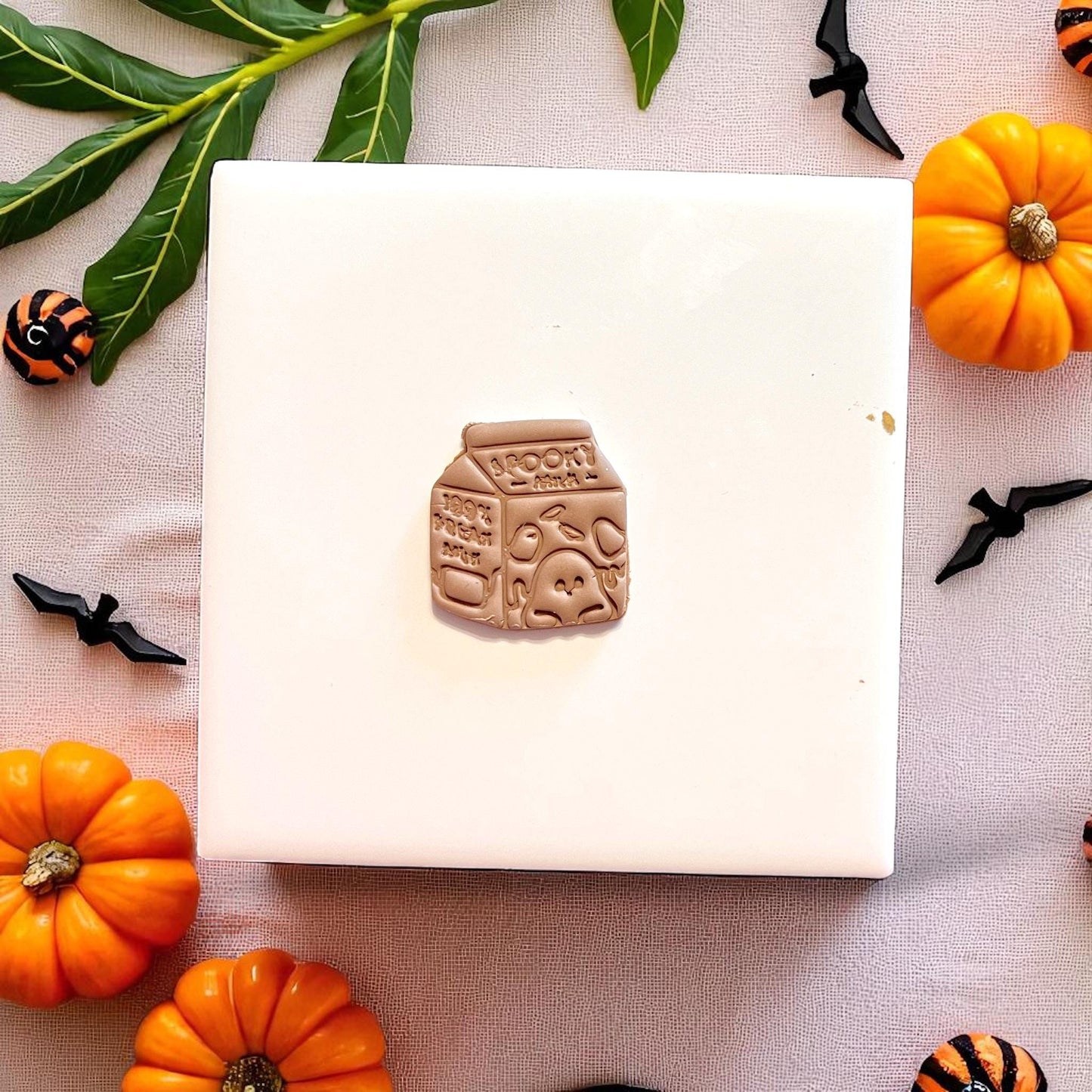 Halloween milk carton clay piece surrounded by pumpkins and bats