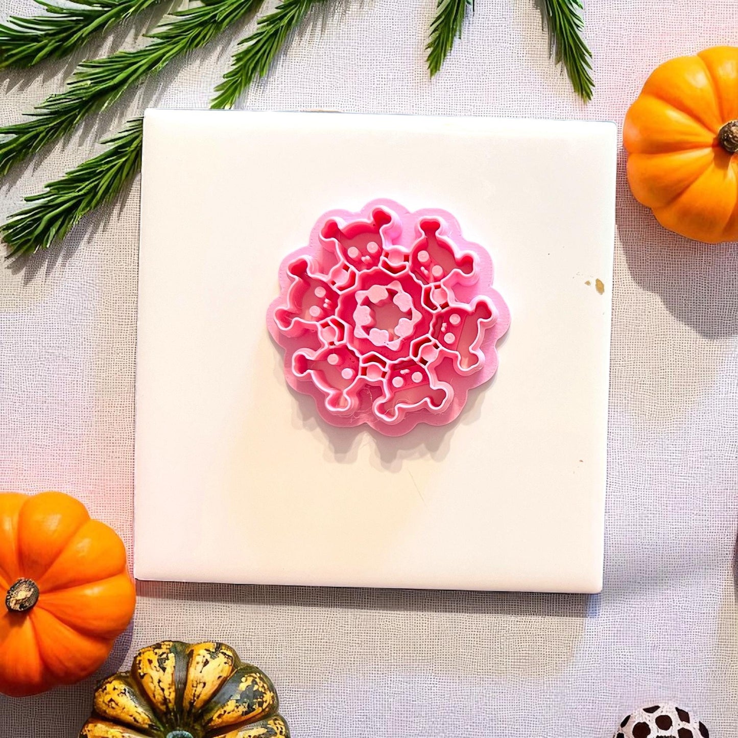 Round skeleton cutter on white tile with pumpkins