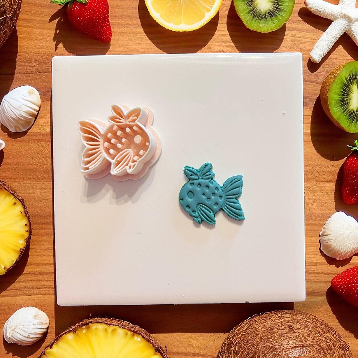 Polymer clay cutter and teal strawberry fish design side by side