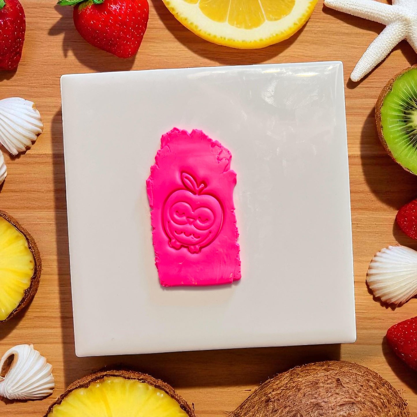 Owl inside apple clay impression on hot pink slab with summer fruit