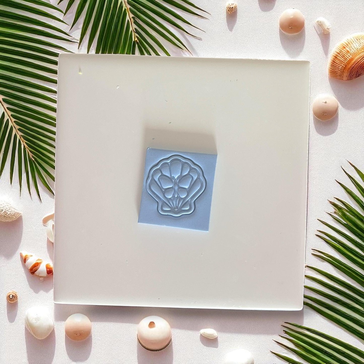 Shell and butterfly clay imprint on blue clay square
