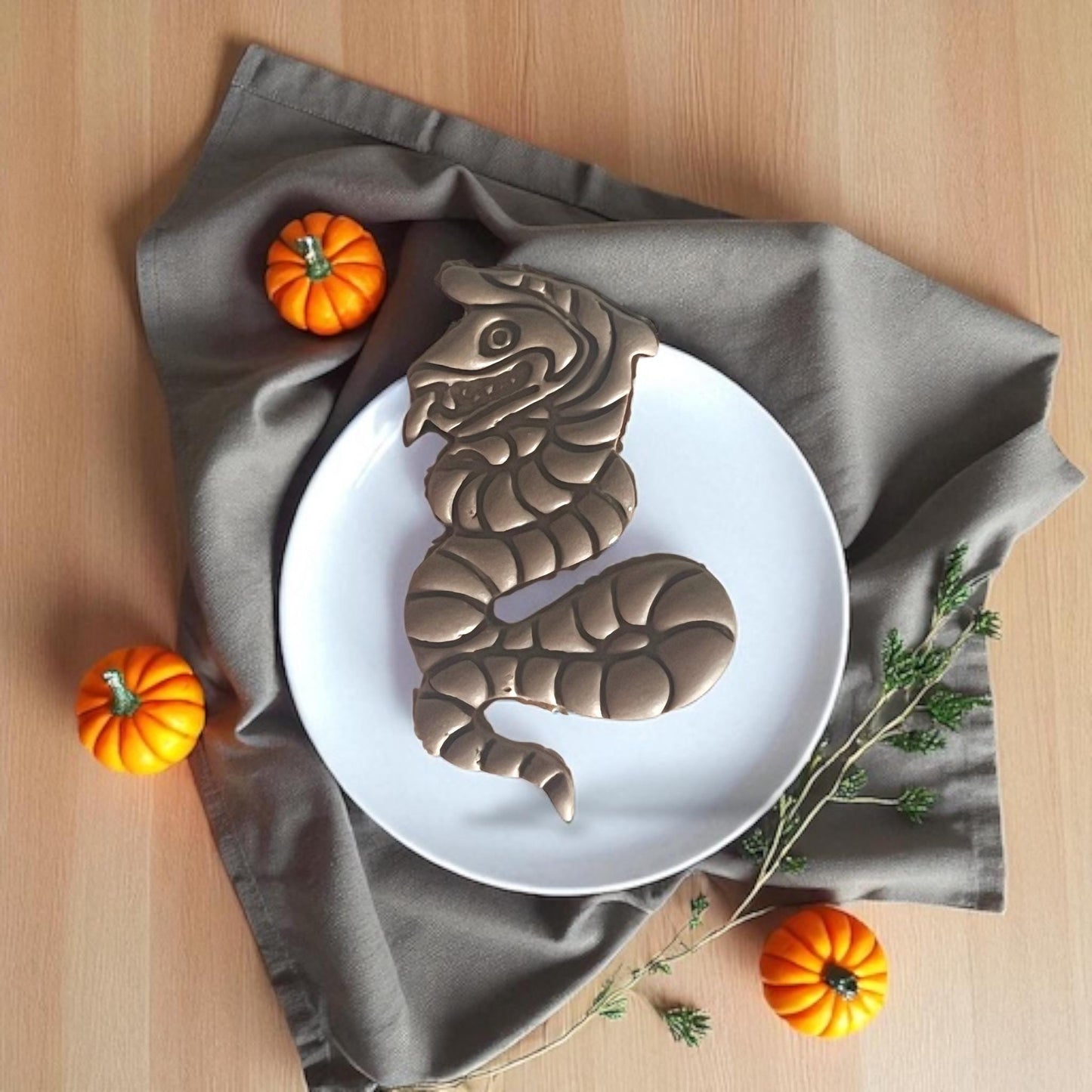 Full-size clay snake on white plate with pumpkins
