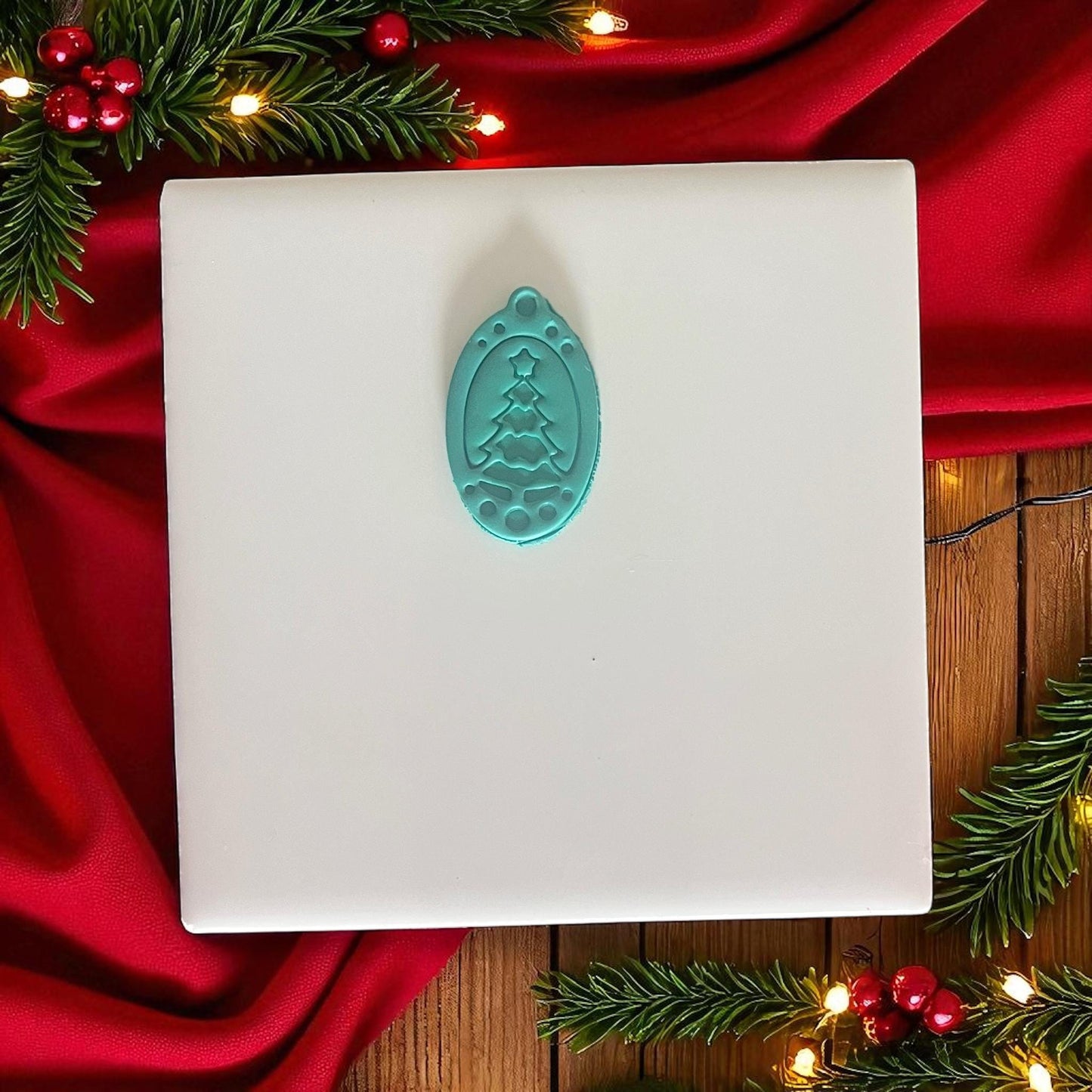 Teal ornament tree cutter displayed on white tile and red holiday fabric