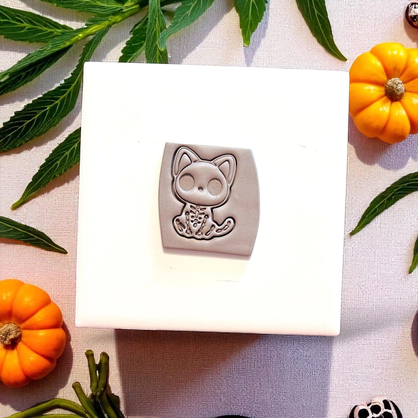 Halloween cat skeleton cutter and clay impression on white block with leaves and pumpkins