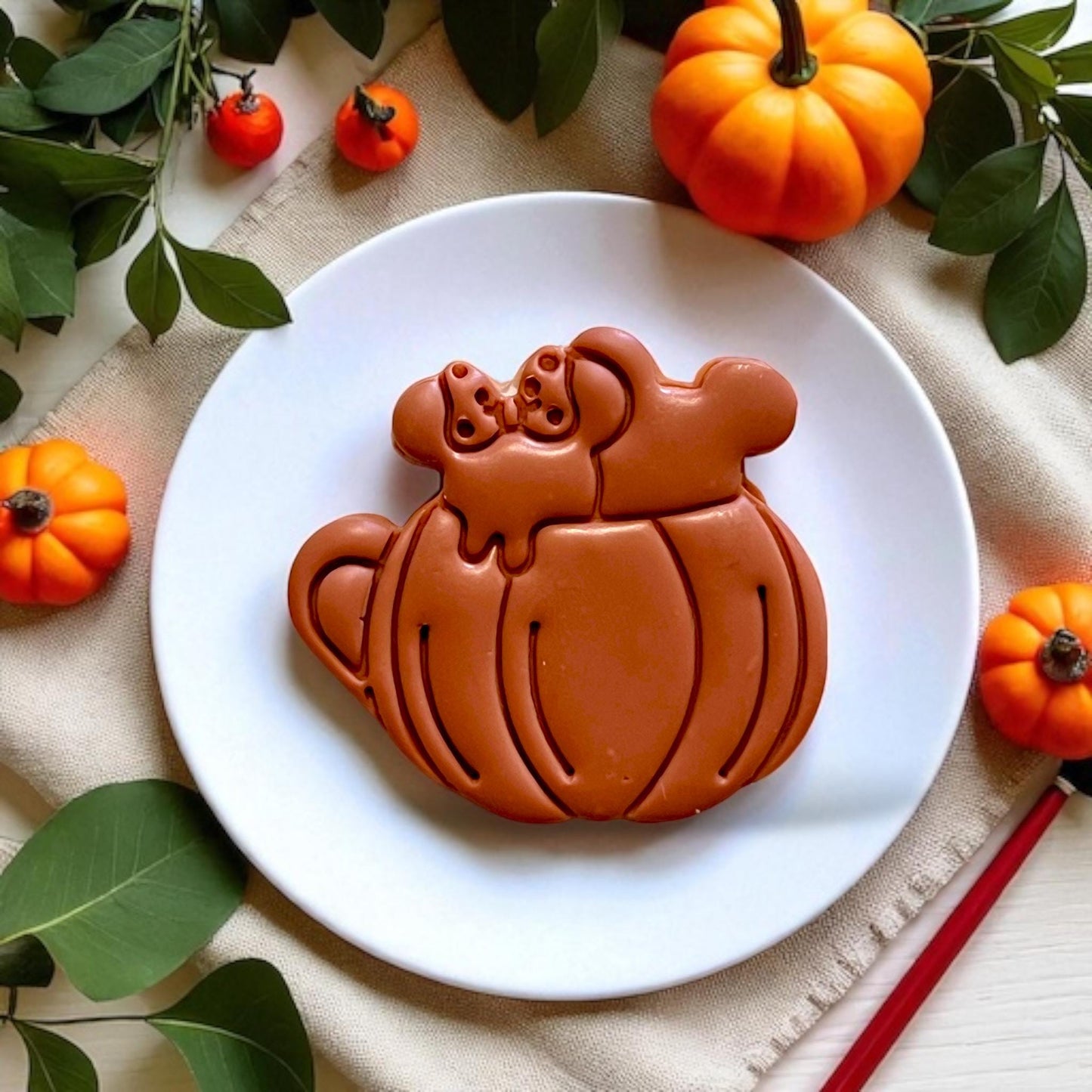 Large pumpkin drink cutout on a white plate with fall foliage and cozy vibes
