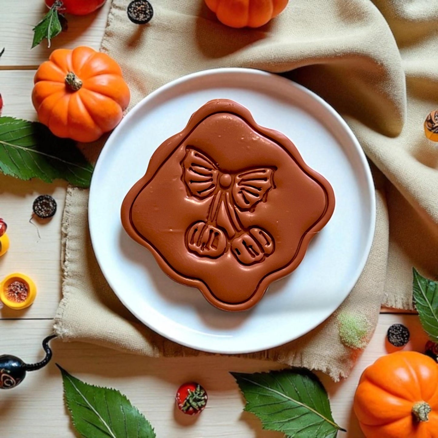 Large framed pumpkin cherry clay piece displayed on a round white plate with fall props