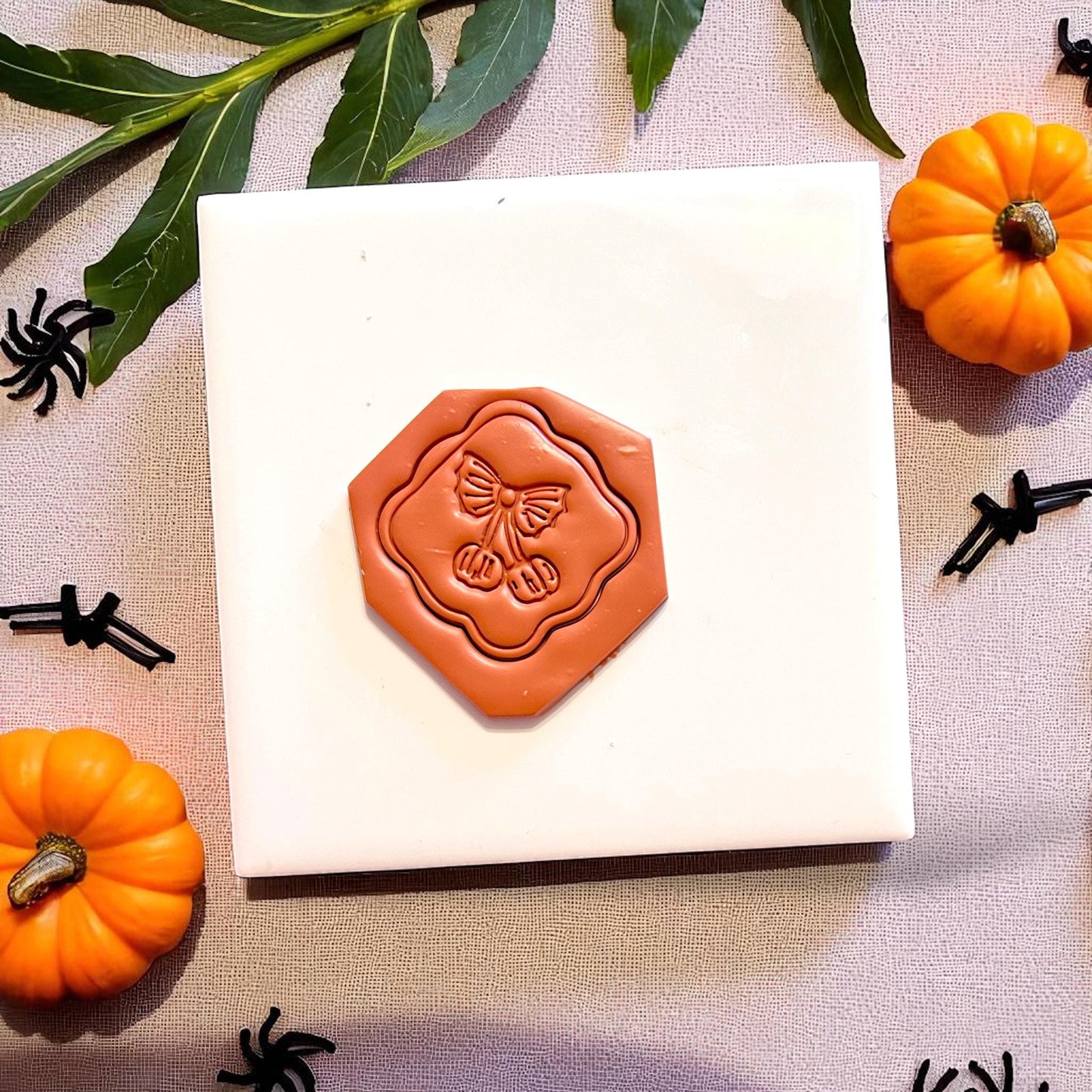 Pumpkin cherry clay imprint on hex tile with fall leaves and spiders