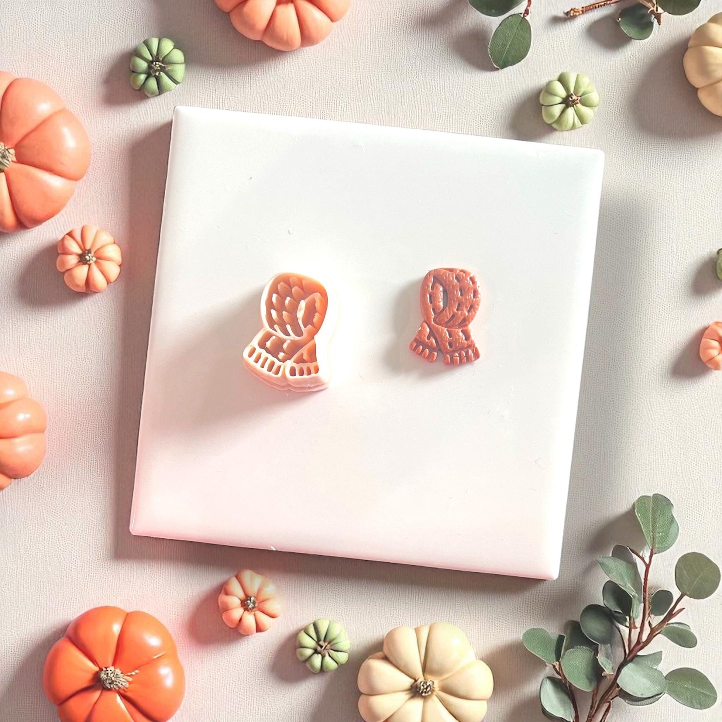 Clay scarf cutter and matching clay cutout shown on white tile with pumpkins