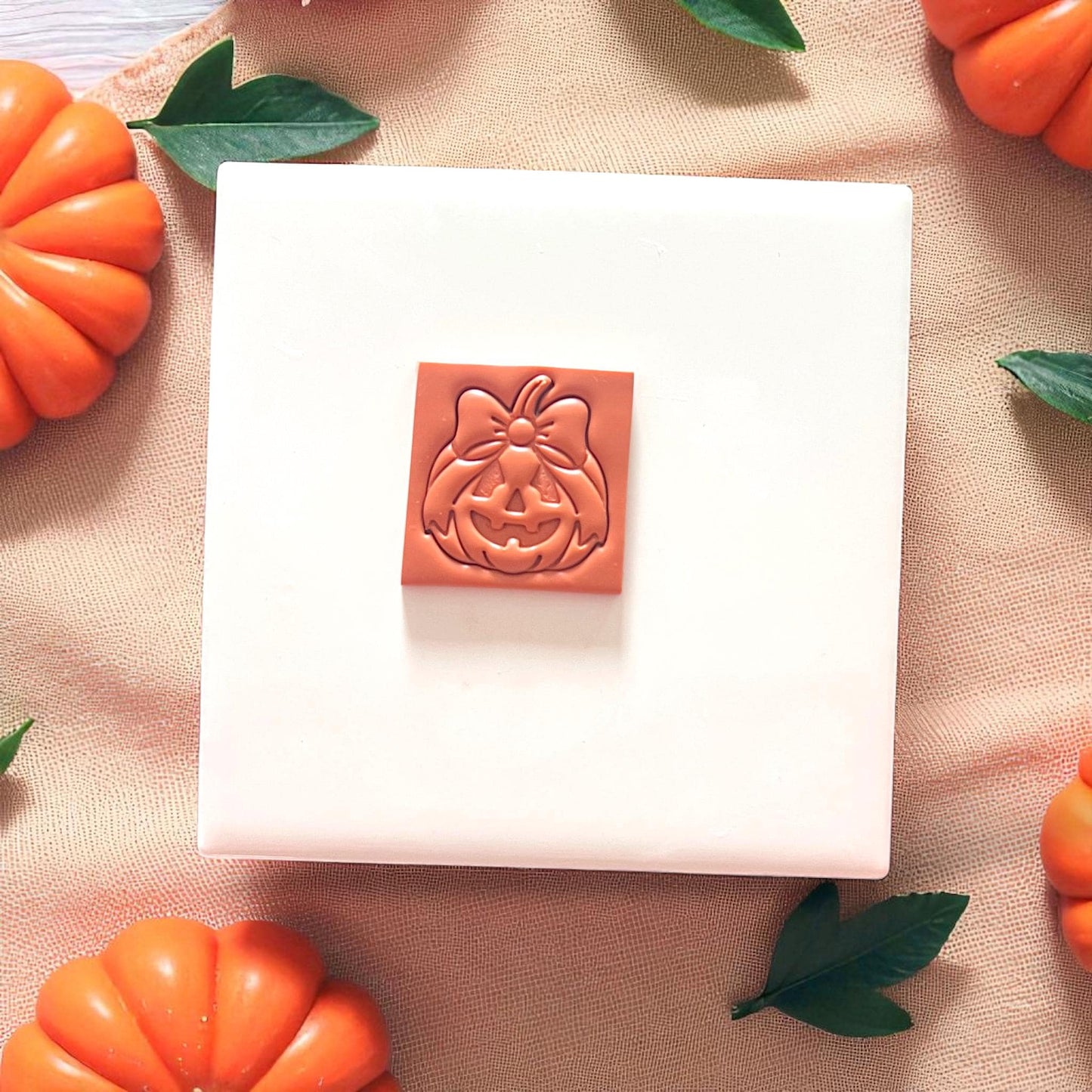 Pumpkin-shaped clay cutter with bow, surrounded by mini pumpkins