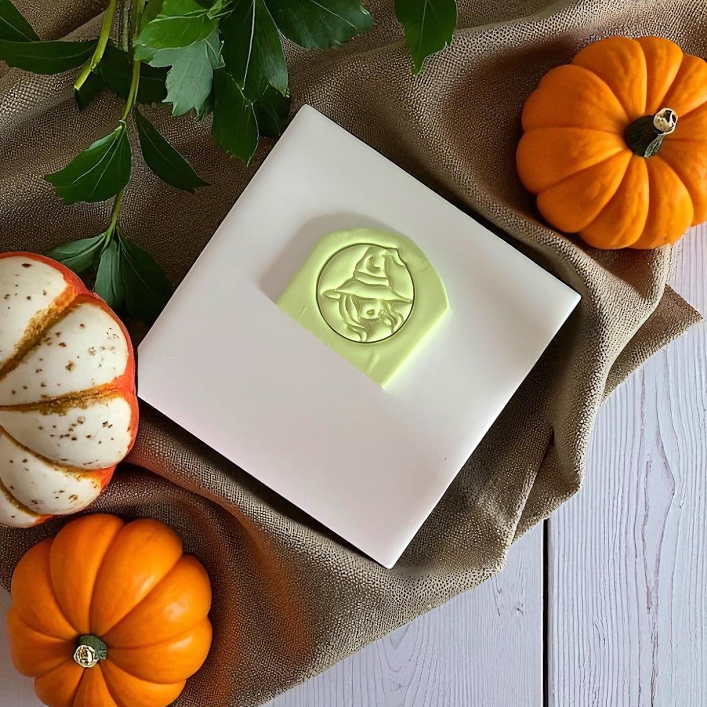 Close-up of sexy witch polymer clay imprint with pumpkins and green leaves