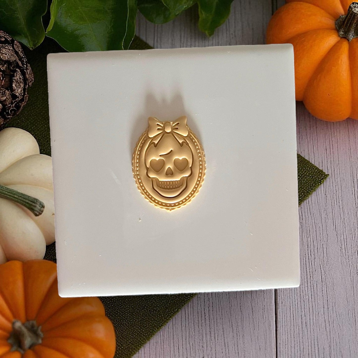 Girly skull cameo clay impression with bow on white background and pumpkins
